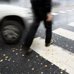 Man on pedestrian crossing in autumn, in danger of being hit by car